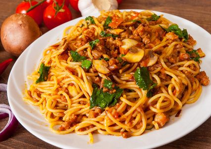 意大利面配蘑菇 蔬菜和肉在一个木制的桌子上的盘子