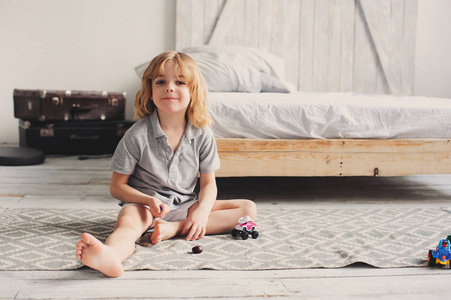 休闲玩具儿童快乐的孩子男孩早上玩玩具汽车在家里.