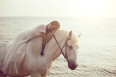 马在海滩上白色连衣裙的女孩