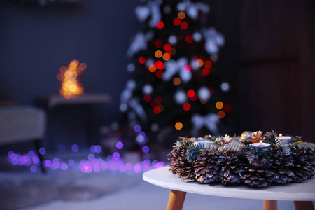 美丽的花圈与松树锥在桌子和圣诞树在黑暗的房间里