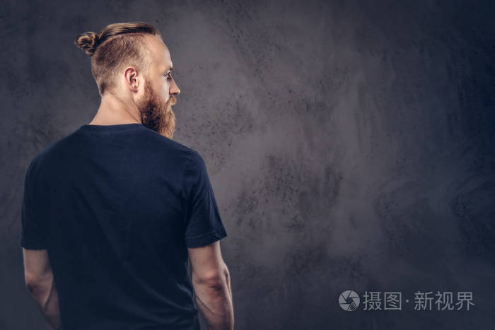 一个身穿黑色t恤衫的红胡子男子的背部视图在深色纹理背景下隔离