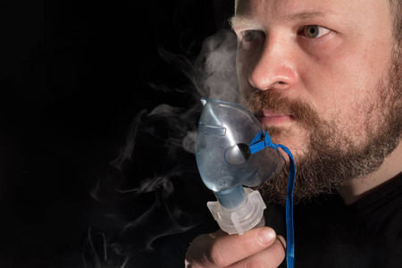 通过雾化器面罩呼吸的人照片