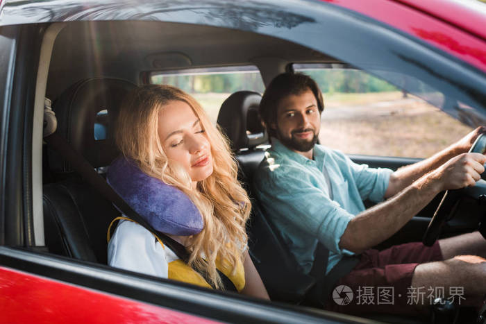 女朋友睡在车里带着旅行枕头, 男朋友开车