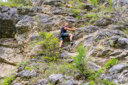 男童登山运动员穿着运动服爬上岩石登上阿尔泰山的顶端没有设备和保险