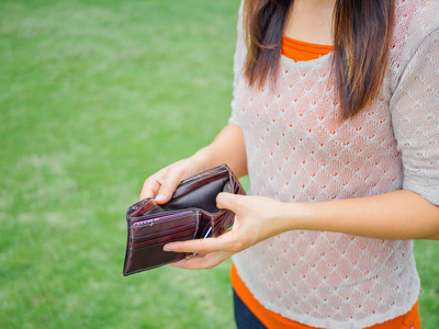 不快乐的破产女人与空的钱包。年轻女子显示她空的钱包。破产