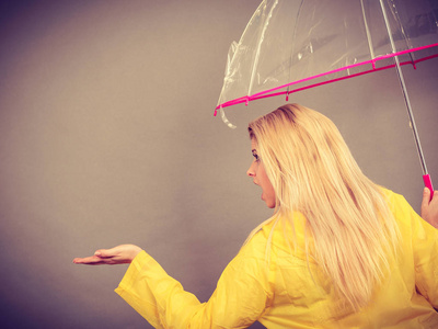 女人穿着雨衣打着伞检查天气