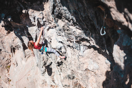 一个女人爬上岩石。运动员在自然的救济下训练。在土耳其攀岩。一个苗条的女孩从事极限运动。积极的爱好。登山者克服了一条艰难的路线。
