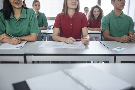 青少年穿着校服和坐在教室里的小学生和女生组