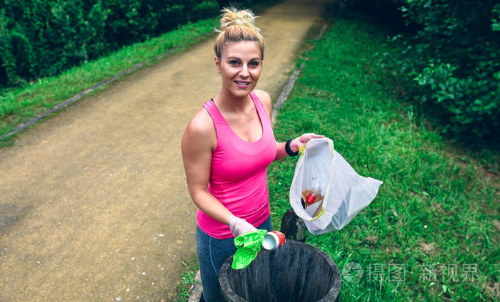 年轻妇女扔垃圾到垃圾桶后plogging