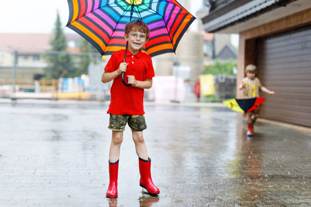 孩子男孩穿上红雨靴,走路用的伞照片