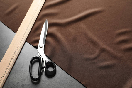 剪刀, 尺子和织物的灰色背景。裁剪设备