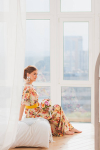 漂亮的女孩坐在一张沙发，一束长连衣裙