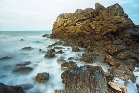 长的暴露海景与泡沫波浪飞溅对泰国的岩石海岸在早晨时间