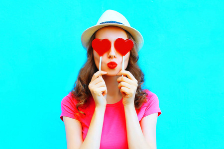 时尚女人做藏红色棒棒糖形状的一颗心一吻