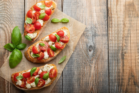 Bruschetta 有西红柿, 芝士干酪和罗勒在一个古老的乡村餐桌上。传统的意大利开胃菜或小吃, 开胃菜来。具有复制空间的顶部