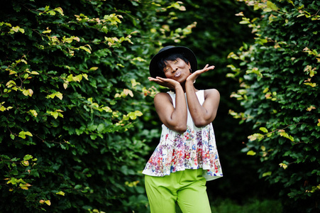 惊人的非洲裔美国模特在绿色的裤子和黑色的帽子摆在公园