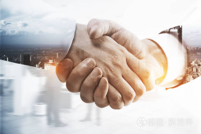 握手在抽象城市背景下的靠拢.二次曝光.团队合作的概念