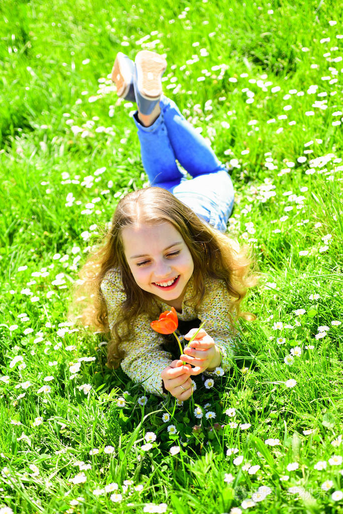 阳光明媚的日子而躺在草地上花季节性过敏的概念女孩在微笑的面孔举行