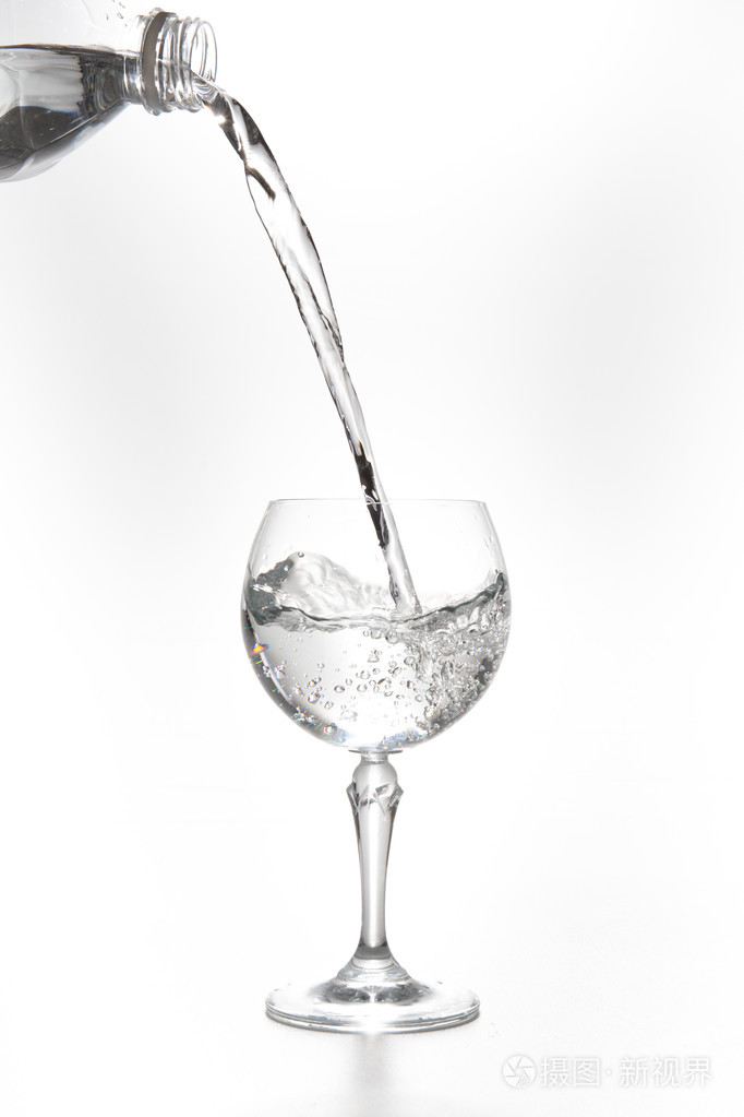 倒水从瓶子变成蓝色背景上的玻璃