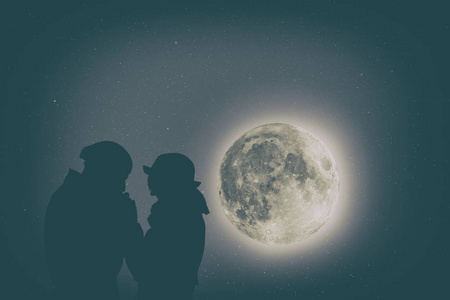 浪漫的男人亲吻女朋友的手, 而站在夜空背景与大月亮和星星照片