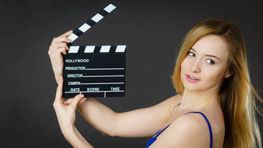 女人持有专业电影石板，电影拍手板。好莱坞生产对象概念。工作室拍摄黑色背景