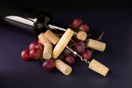 许多酒瓶塞和螺旋形红葡萄黑色背景