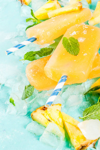自制菠萝冰棒冰与新鲜菠萝片和薄荷, 在浅蓝色背景复制空间照片