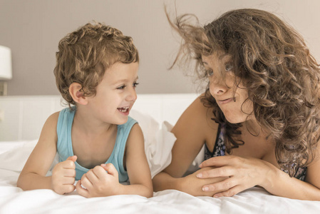 一个女人和她的儿子在床上玩耍, 示意