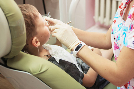 一个在牙科诊所接受牙医接待的小男孩。儿童牙科, 儿科牙科。女性 stomatologis
