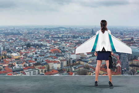 一个年轻的 careeroriented 女商人, 在城市的屋顶上有喷气机翼。