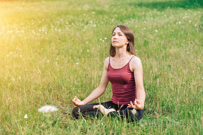 美丽的女孩在公园里做瑜伽.放松, 休息, 与自然和谐相处