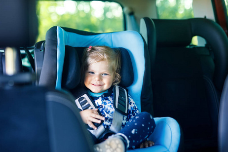 可爱的小女孩, 蓝眼睛坐在汽车安全座椅。蹒跚学步的孩子去家庭度假和 jorney