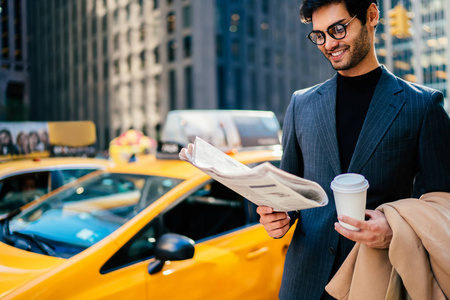 成功的男性执行经理优雅的正式穿着满意的财经新闻从新闻站在纽约大街上, 繁华的商人阅读晨报等待税收
