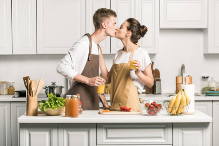 年轻情侣在厨房里做沙拉时接吻