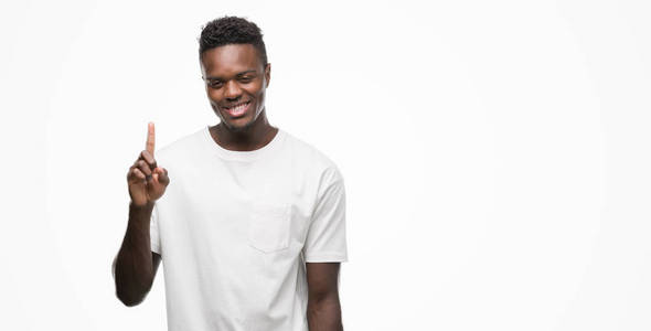 年轻的非洲裔美国人穿着白色 t恤显示和指着手指第一, 而微笑着自信和快乐