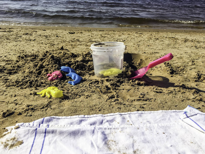 塑料彩色形状, 铲子和小桶为儿童玩沙滩上的沙子。婴儿塑料模具躺在沙子上的滩涂。夏日阳光明媚的玩具在沙滩上