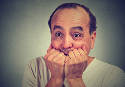 害怕的中年人咬着指甲,惊慌失措照片