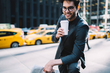 繁荣的商人在优雅的西装和眼镜享受香气咖啡去在曼哈顿花休息, 微笑自信的男性老板在正式的装备持有空白杯满意 beverag