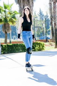 美丽的年轻女子在大街上滑板的练习