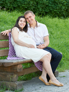 幸福的夫妇，在户外的夏天城市公园 孕妇 阳光灿烂的日子和绿草，美丽人肖像