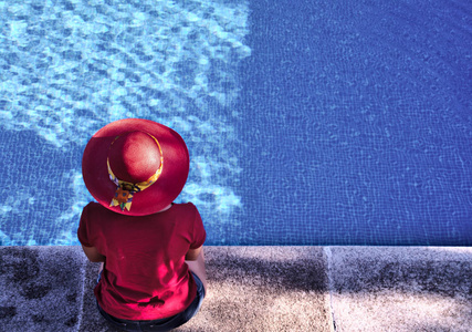 妇女在游泳池, 穿着红色的小屋和衬衫, 看着蓝色的水