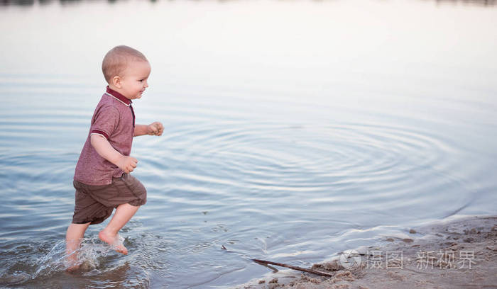 孩子在湖岸边散步水和沙子。春季露天活动