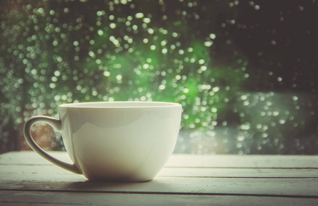 一杯热茶在窗外的背景雨中。选择性聚焦
