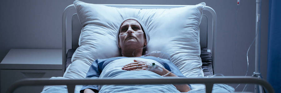 封面照片的一个孤独, 生病的女人躺在病床上, 呼吸管和头巾照片