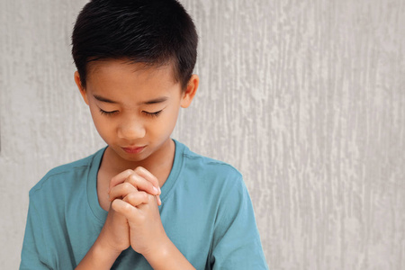 亚洲男孩儿童祈祷与眼睛关闭, 基督教信仰概念照片