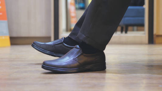 穿棕色新时尚鞋的男性脚.商人在鞋市场购物照片