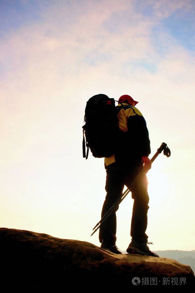 与大背包徒步旅行者站在岩石看法点以上迷雾笼罩的山谷.