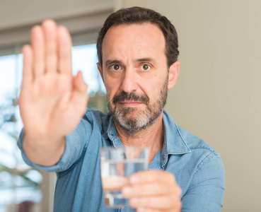 中年男子喝一杯水用张开的手做停止标志以严肃和自信的表达, 防御姿态