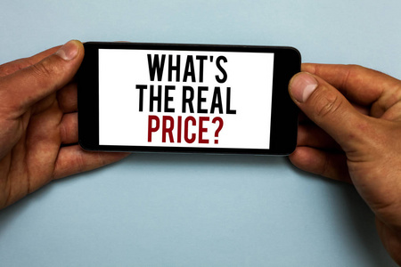 字写文本什么是真正的价格问题。为房地产或商务人员提供实际价值的商业概念在阴影蓝色地板上手持带有红色和黑色字母的智能手机