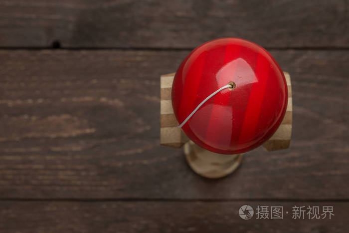 红剑站在黑暗的木制仿古背景。传统的日本玩具。准确性和灵活性的发展。孩子们，孩子们，球游戏
